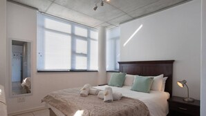 A bedroom with a bed, a nightstand, a mirror, and a window. - Key West 417 by Ctha (Milnerton)