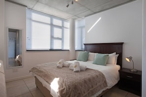 Una camera da letto con un letto, un comodino, uno specchio e una finestra.