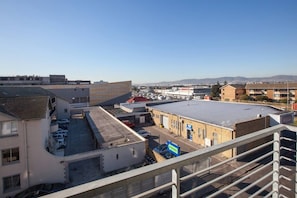 A commercial area with a parking lot, a building with a blue sign, and a clear sky.