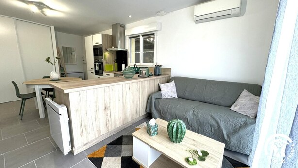 Une cuisine moderne avec un îlot central en bois, un canap é gris et une table basse agrémentée d’objets décoratifs.