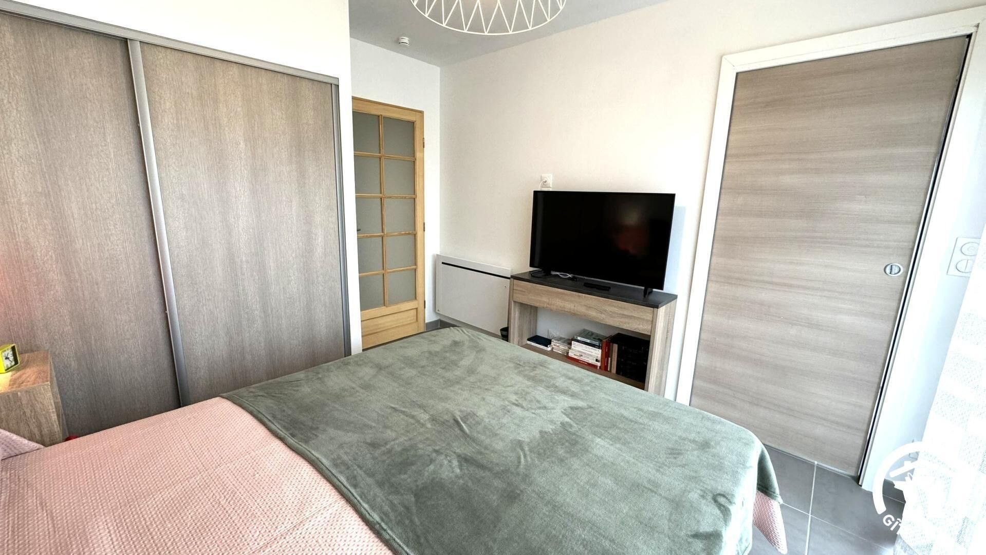 Ein Schlafzimmer mit einem Bett, einem Fernseher auf einem Schrank, einem Kleiderschrank und einer Schiebetür.