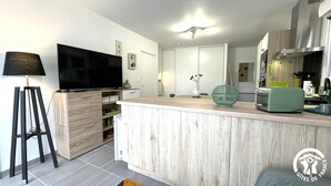 Une cuisine moderne dotée d’un îlot central en bois, d’un téléviseur à écran plat et d’un coin repas avec une table et des chaises.
