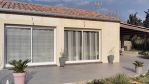 Une maison moderne dotée de grandes portes-fenêtres coulissantes, d’un toit en tuiles et d’une antenne parabolique.