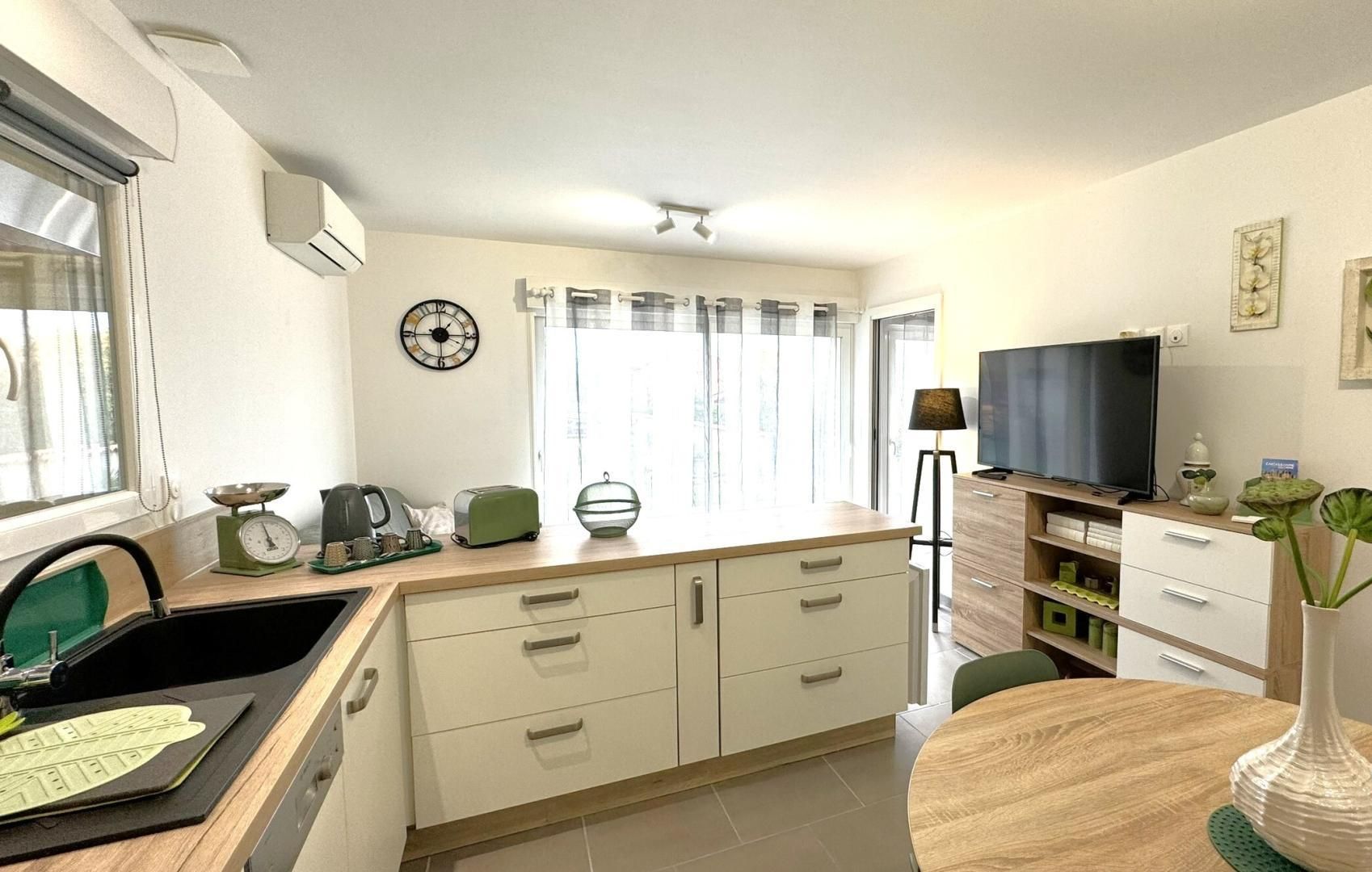 Una cucina moderna con zona pranzo, televisione e orologio a parete.