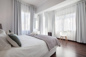A modern hotel room with a large bed, a desk, and a chair.