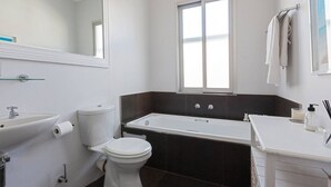 Un baño con inodoro, lavamanos, bañera y ventana.