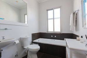 A bathroom with a toilet, sink, bathtub, and a window.