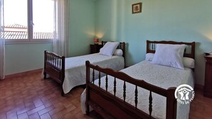 A room with two single beds, a window with curtains, a chandelier, and a small table with a lamp. - La barnede - BAGES - Gîte (BAGES)