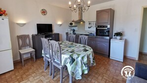 A compact kitchen with a dining area, a television, and a chandelier. - La barnede - BAGES - Gîte (BAGES)