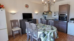 A compact kitchen with a dining area, a television, and a chandelier.