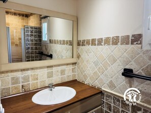 A bathroom with a wooden vanity, a white sink, and a mirror. - Petite Pinède - CANET D'AUDE (CANET D'AUDE)