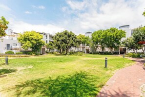 A residential area with modern buildings, a grassy lawn, and a paved walkway.