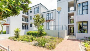 Un edificio residencial moderno de varios pisos con balcones, un patio empedrado y una farola.