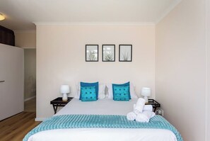 Una habitación de hotel con una cama, dos mesitas de noche y tres cuadros enmarcados en la pared.