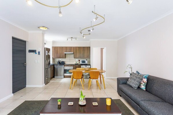 A modern apartment with a dining area, kitchen, and living room.
