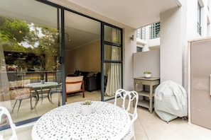 Un balcone con tavolo e sedie, un divano, una piccola scrivania e un oggetto coperto.