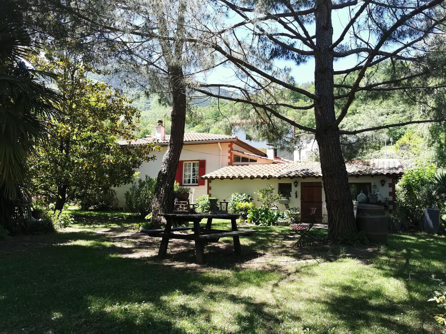 A house with a tiled roof, surrounded by trees and a grassy yard.
