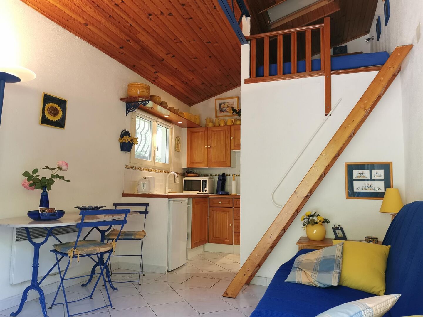 A compact living space with a kitchen, dining area, and a staircase leading to an upper level.
