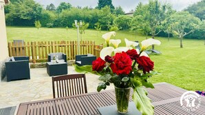 A patio with a table, chairs, and a vase of flowers. - Gîte le Bouirou - LES MARTYS (LES MARTYS)