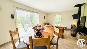 A spacious living room with a wooden dining table, a sofa, and a fireplace. - Gîte le Bouirou - LES MARTYS (LES MARTYS)