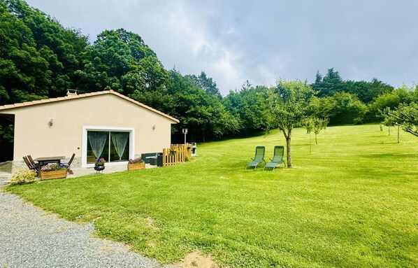 A house with a patio, a lawn, and a tree.