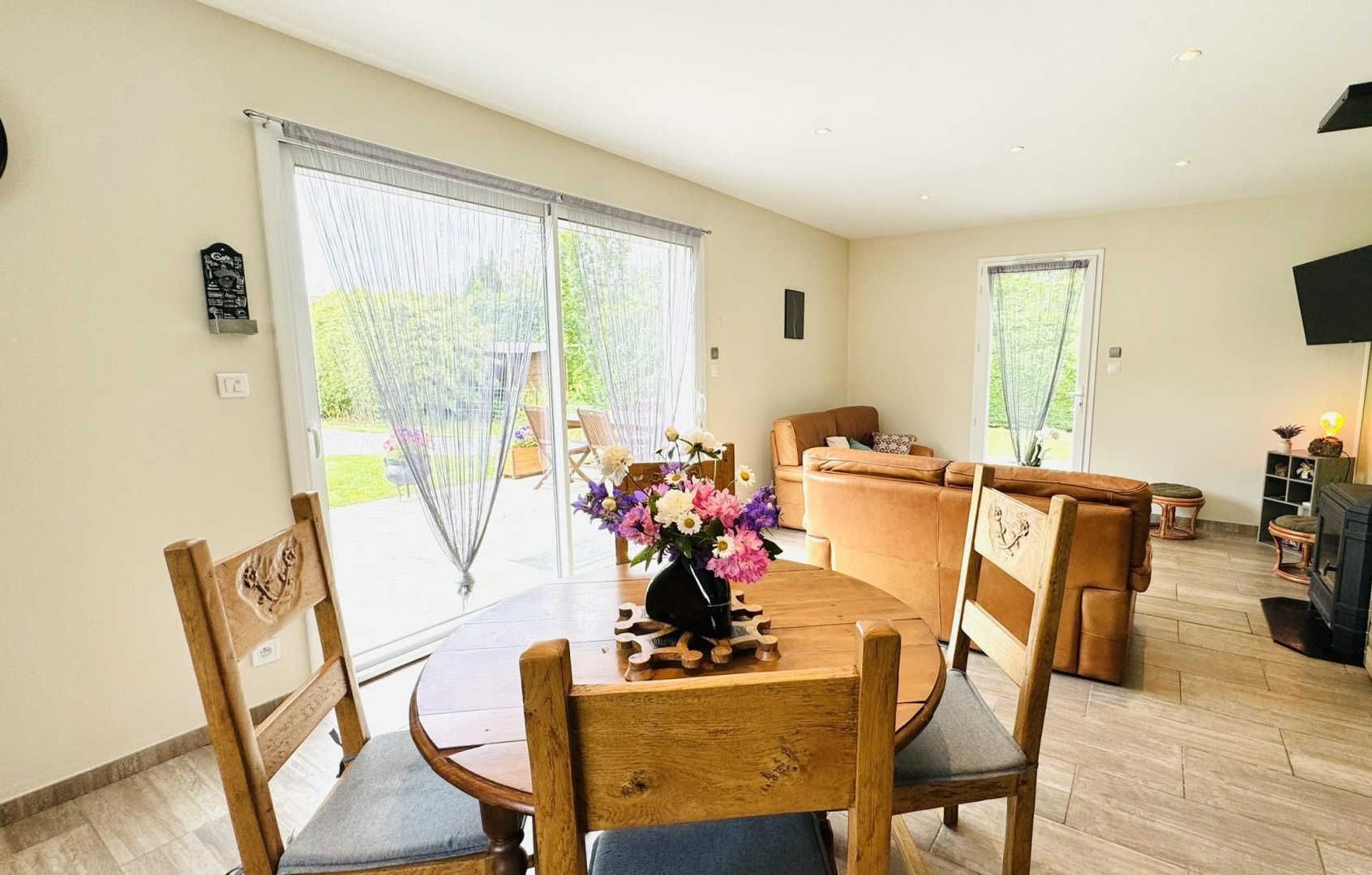 Een ruime woonkamer met een houten eettafel, een bank en een open haard.