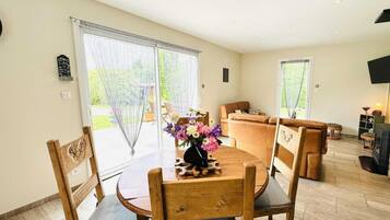 Een ruime woonkamer met een houten eettafel, een bank en een open haard.