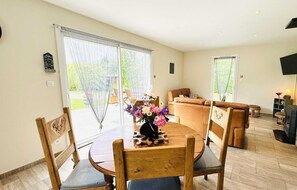 A spacious living room with a wooden dining table, a sofa, and a fireplace.