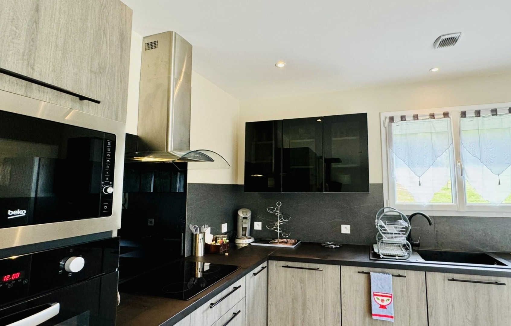 Een moderne keuken met een inbouwfornuis, magnetron en zwarte kasten.
