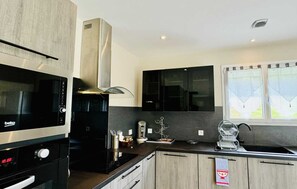A modern kitchen with a built-in stove, microwave, and black cabinets.