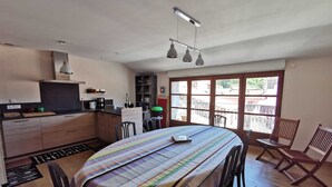 A compact kitchen with modern appliances, a dining area with a striped tablecloth, and large windows offering a view of the outside.