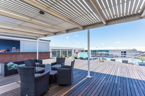 Une terrasse extérieure couverte, aménagée avec des meubles en osier, une piscine et une vue sur le pont du navire.