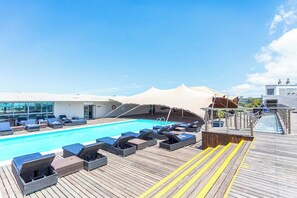 Un espace piscine avec des chaises longues et une terrasse en bois.