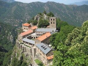 A historic building with multiple structures, including a tower, situated on a hillside with a mountainous backdrop. - La clé des champs - SAHORRE (SAHORRE)