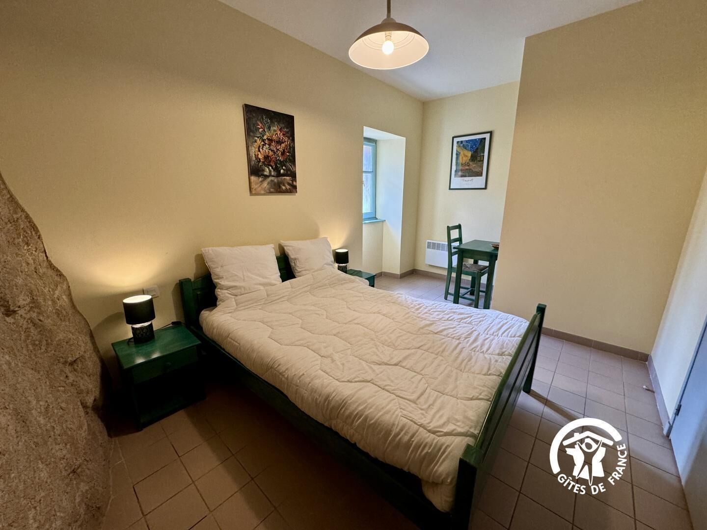 Une chambre à coucher avec un lit, des tables de chevet, une chaise et un bureau.