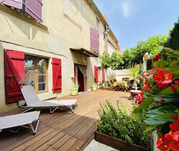 A wooden deck with two lounge chairs, a table, and potted plants.