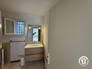 A modern bathroom with a white sink, wooden vanity, and a large mirror above it.