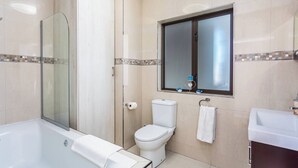 A modern bathroom with a glass shower enclosure, a toilet, a sink, and a bathtub. - Beachfront 3br | Ocean Views & bbq balcony by ctha (Cape Town)
