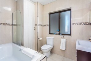Un bagno moderno con box doccia in vetro, un water, un lavandino e una vasca da bagno.