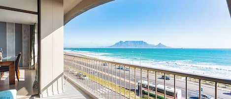 A balcony with a view of the ocean and a distant mountain.
