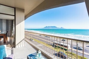 Un balcon avec vue sur l’océan et sur une montagne lointaine.