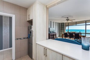 A modern kitchen with a built-in refrigerator, a dining area with a view of the ocean, and a ceiling fan.