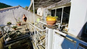 A balcony with a white railing, potted plants, and a terracotta pot. - La Maison du Berger - CAUNES MINERVOIS (CAUNES MINERVOIS)