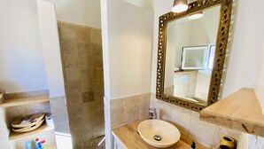 A bathroom with a beige sink, a wooden vanity, a large mirror with an ornate frame, and a shower area with stone tiles. - La Maison du Berger - CAUNES MINERVOIS (CAUNES MINERVOIS)