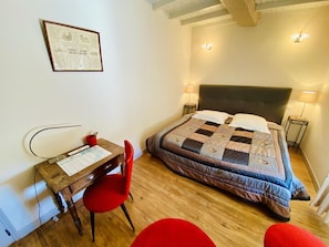 Een slaapkamer met een bed, nachtlampjes, een bureau met stoel, en een ingelijst diploma aan de muur.