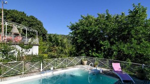 A swimming pool with a wooden deck, surrounded by a white fence and lush greenery. - La Maison du Berger - CAUNES MINERVOIS (CAUNES MINERVOIS)