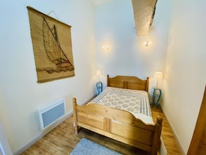 Ein Schlafzimmer mit einem hölzernen Bett, zwei Nachttischlampen, einem Wandteppich und einer Heizung.