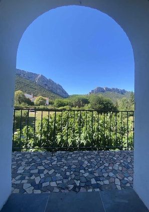 A balcony with a view of a mountainous landscape, a tiled floor, and a metal railing.