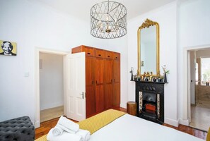 Een slaapkamer met een bed, een kledingkast, een spiegel en een open haard.