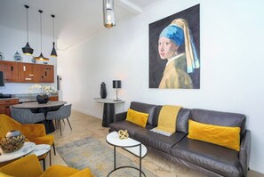 Een moderne woonkamer met een bank, stoelen, een salontafel en een schilderij aan de muur.